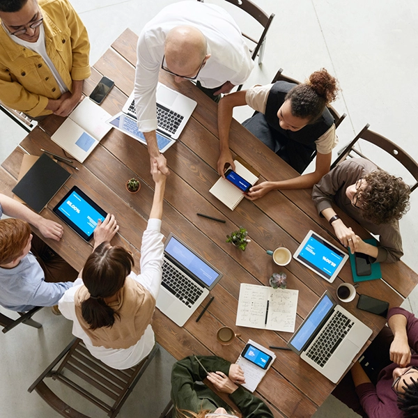 team of 8 collaborating at a desk with computers